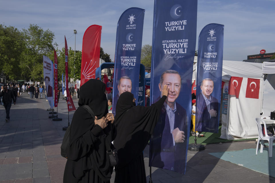 FILE - A woman gestures in front of a banner with an image of Turkish President and People's Alliance's presidential candidate Recep Tayyip Erdogan, in Istanbul, Turkey, Monday, May 8, 2023. Turkey is heading toward presidential and parliamentary elections on Sunday May 14, 2023. (AP Photo/Khalil Hamra, File)