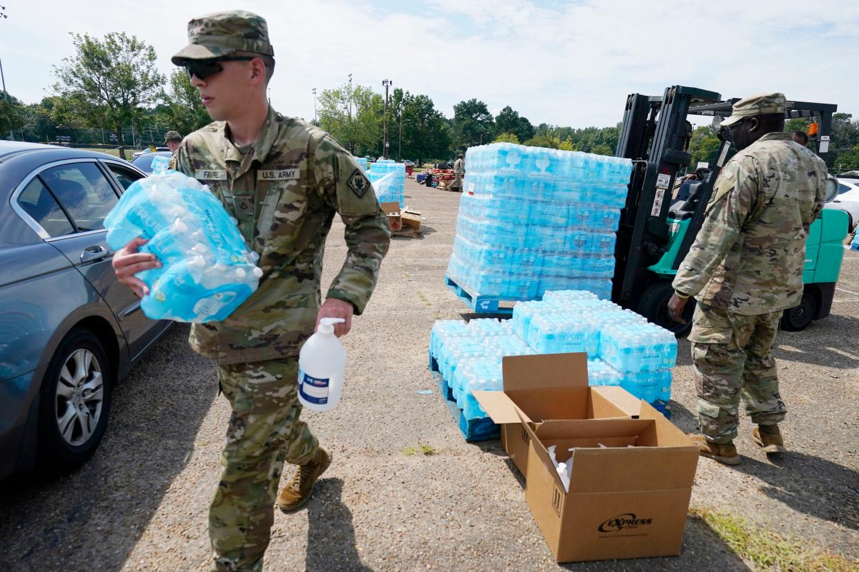 Mississippi National Guardsmen carry cases of drinking water and a bottle of hand sanitizer to Jackson, Miss., residents, Friday, Sept. 2, 2022, at Smith Wills Stadium. 