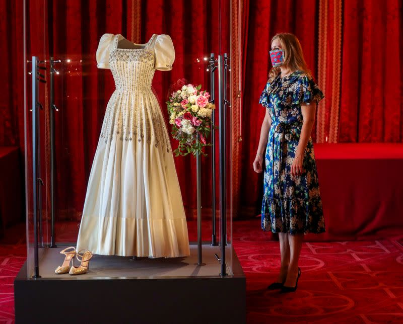 La princesa británica Beatriz de York se encuentra junto a su vestido de novia, que originalmente usó la reina Isabel de Inglaterra en la década de 1960, antes de que se exhiba públicamente en el Castillo de Windsor