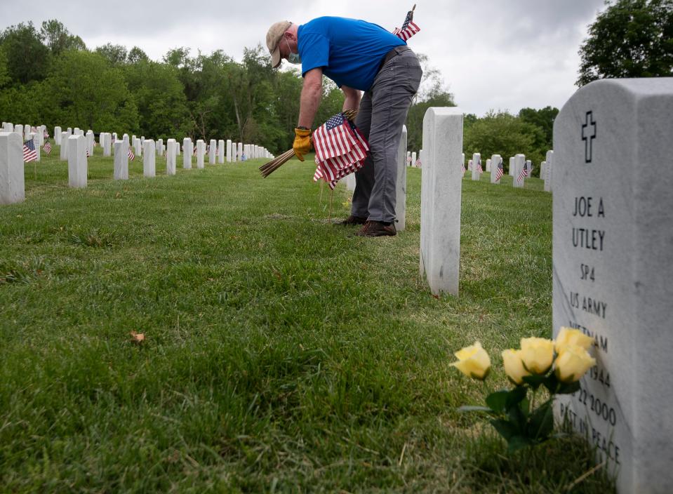 Dan Wolgast from the Tennessee Department of Veteran Services volunteers to place flags at gravestones at Middle Tennessee Veterans Cemetery on Tuesday, May 19, 2020, in Nashville, Tenn. in preparation for Memorial Day.