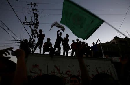 FILE PHOTO - A Palestinian waves a Hamas flag (R) in Gaza City August 26, 2014. REUTERS/Suhaib Salem/File Photo