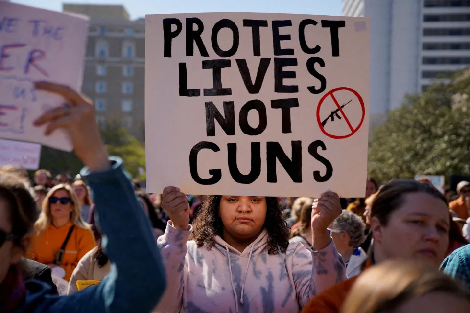 A large group of protesters, one holding a sign saying: Protect Lives Not Guns.