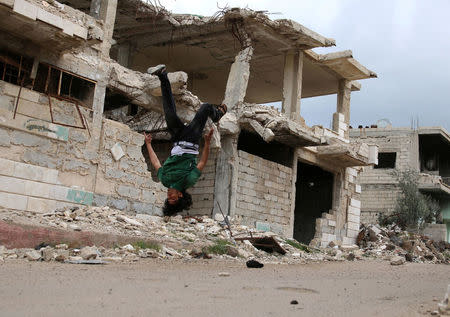 Parkour coach Ibrahim al-Kadiri, 19, demonstrates his Parkour skills near damaged buildings in the rebel-held city of Inkhil, west of Deraa, Syria, April 7, 2017. The team records their performances in photos and videos, which they post on social media. REUTERS/Alaa Al-Faqir