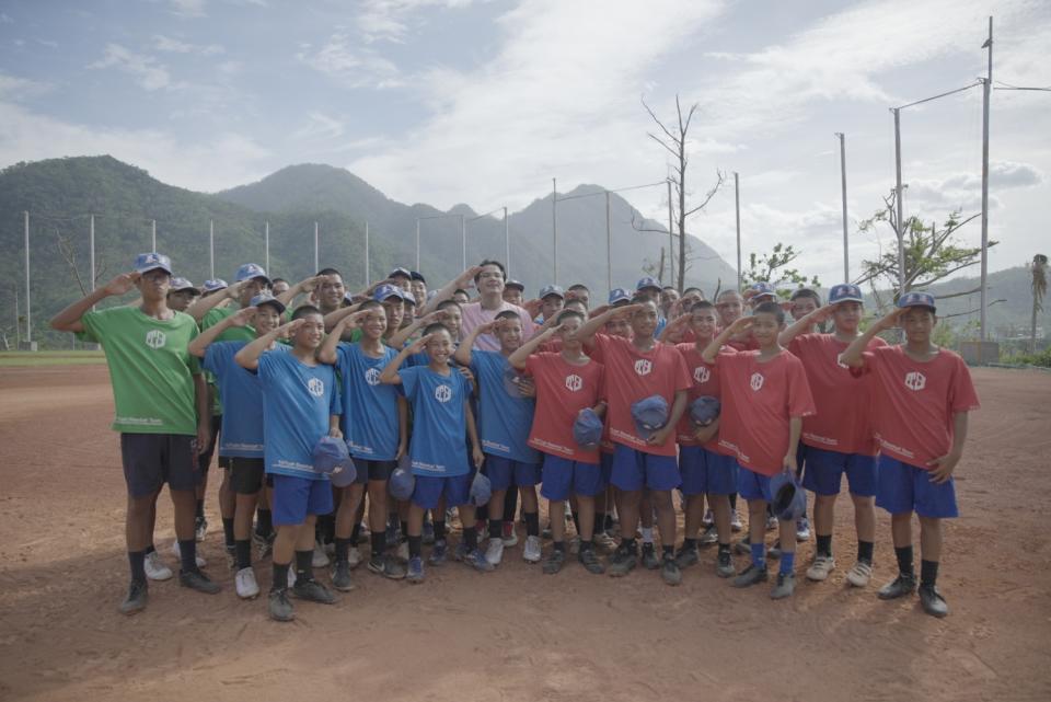 張育成與泰源國中棒球隊的小學弟合影。（好友多媒體製作有限公司提供）