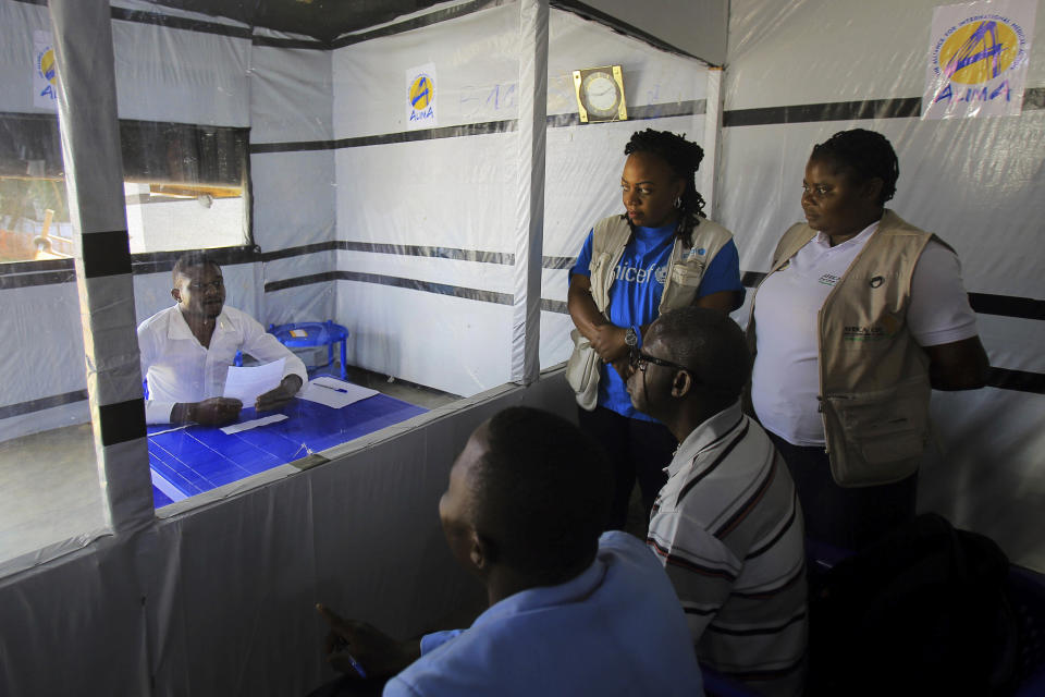 In this Saturday, July 20, 2019 photo, Claude Mabowa Sasi, 21, who had lost his mother, a brother and a sister to Ebola, takes his college-entry exam in an isolation room at an Ebola treatment center in Beni, Congo. It had been his mother's greatest hope that he would go to college. Unable to sit in the same room with other college test-takers, Mabowa took it safely behind a window. After finishing, he held his pages up one by one to the window so they could be photographed with a smartphone and then emailed to officials for scoring. (AP Photo/Al-Hadji Kudra Maliro)