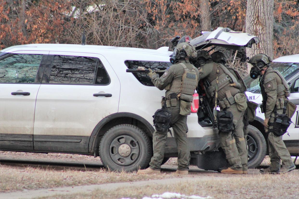 Great Falls police officers in full body armor and wearing gas masks take a position outside the house at 2812 1st Ave. North where Monday's standoff took place.