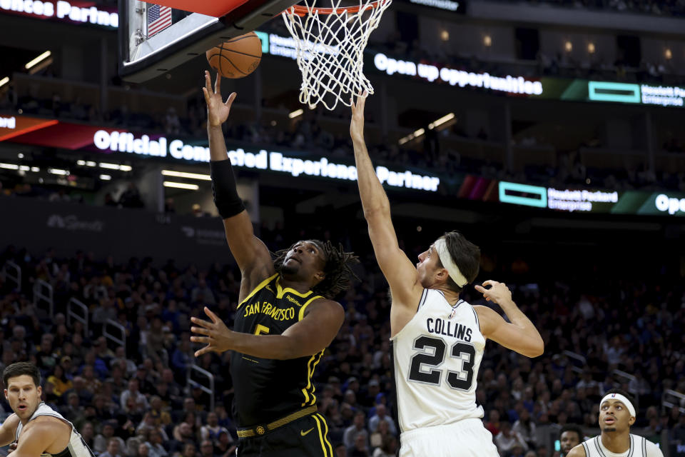 Golden State Warriors forward Kevon Looney, center left, shoots against San Antonio Spurs forward Zach Collins (23) during the first half of an NBA basketball In-Season Tournament game in San Francisco, Friday, Nov. 24, 2023. (AP Photo/Jed Jacobsohn)