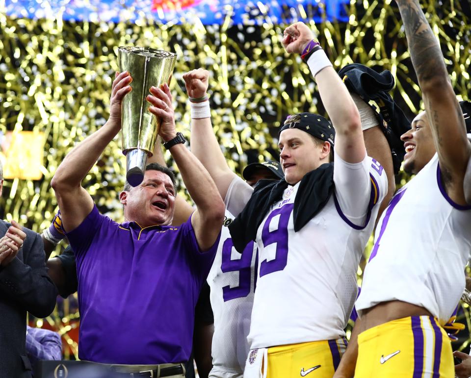 LSU coach Ed Orgeron hoists the national championship trophy with quarterback Joe Burrow after the Tigers defeated Clemson in the College Football Playoff national championship game at Mercedes-Benz Superdome.