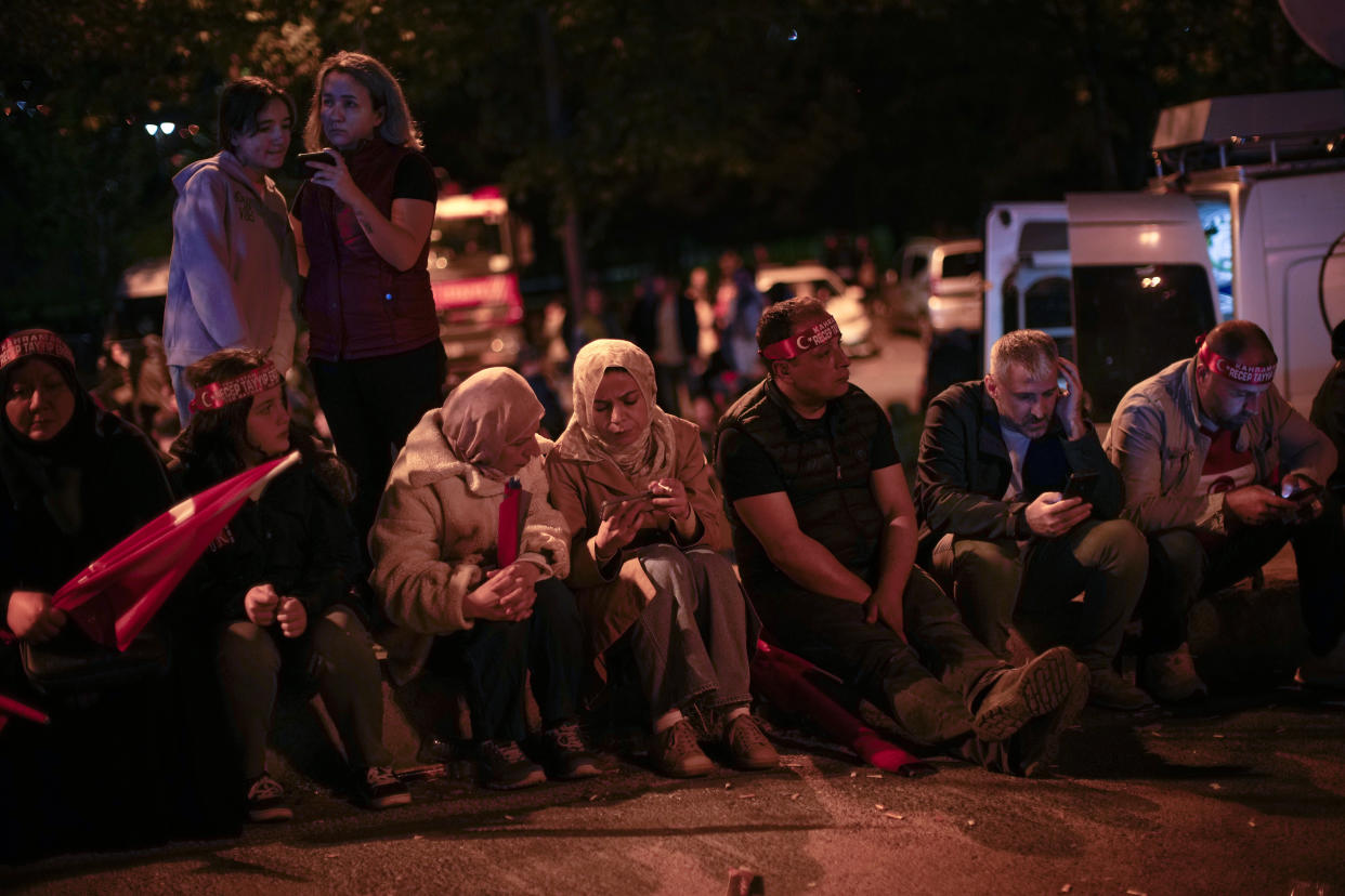 Supporters of Turkish President Recep Tayyip Erdogan follow news on their smartphones outside AKP (Justice and Development Party) headquarters in Istanbul, Turkey, Sunday, May 14, 2023. More than 64 million people, including 3.4 million overseas voters, were eligible to vote. (AP Photo/Francisco Seco)