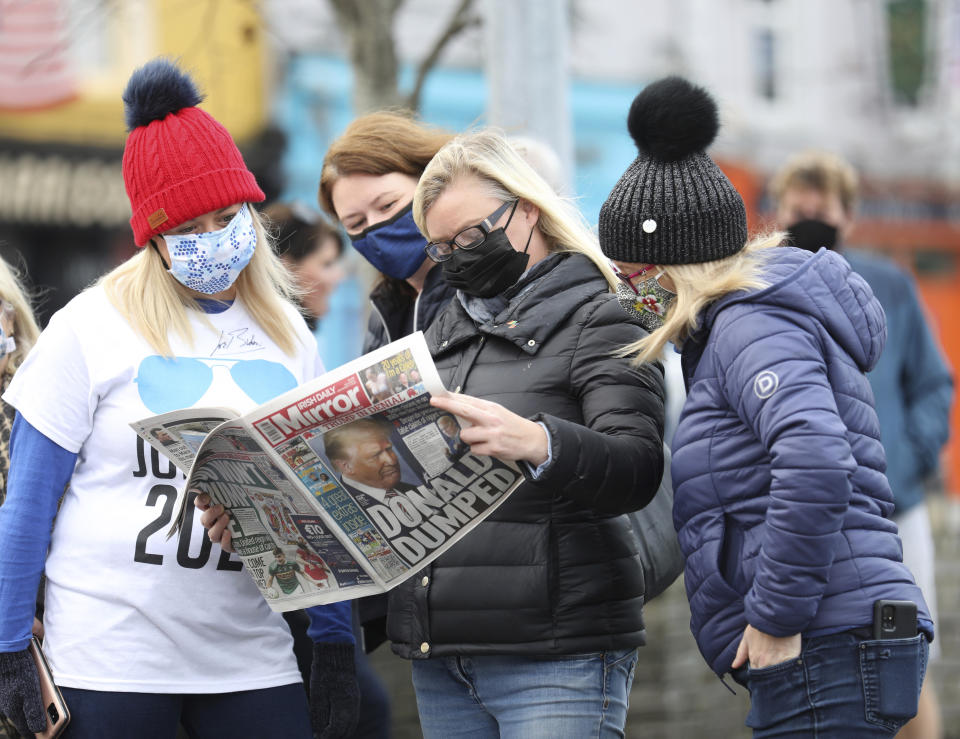 Residents read a copy of their local paper in the town of Ballina, North West of Ireland, the ancestral home of President elect Joe Biden, Saturday, Nov. 7, 2020. Biden was elected Saturday as the 46th president of the United States, defeating President Donald Trump in an election that played out against the backdrop of a pandemic, its economic fallout and a national reckoning on racism. (AP Photo/Peter Morrison)