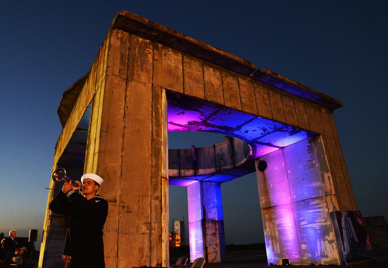 U.S. Navy Petty Officer 2nd Class Jimmie Gilbert plays Taps at the base of the launch platform Jan. 27 during a ceremony memorializing the anniversary of the Apollo 1 fire at Launch Complex 34.