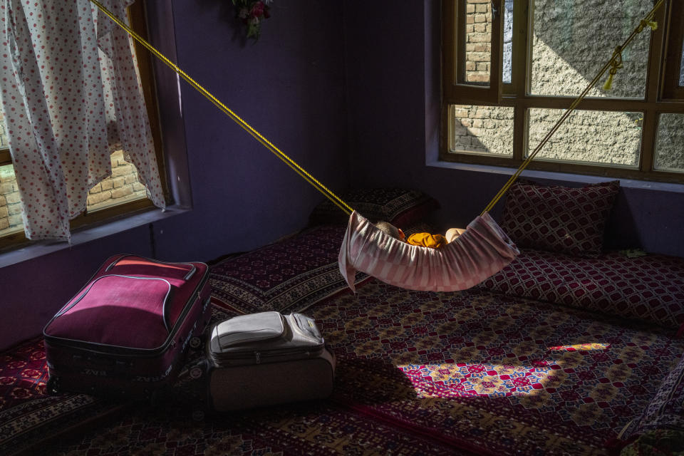 A child sleeps on a hammock next to packed suitcases from the Jawed family in Kabul, Afghanistan, Monday, Sept. 27, 2021. Despite the family unsuccessfully trying to leave Afghanistan since the arrival of the Taliban, two suitcases packed with clothes and some land-property documents are set to go. (AP Photo/Bernat Armangue)