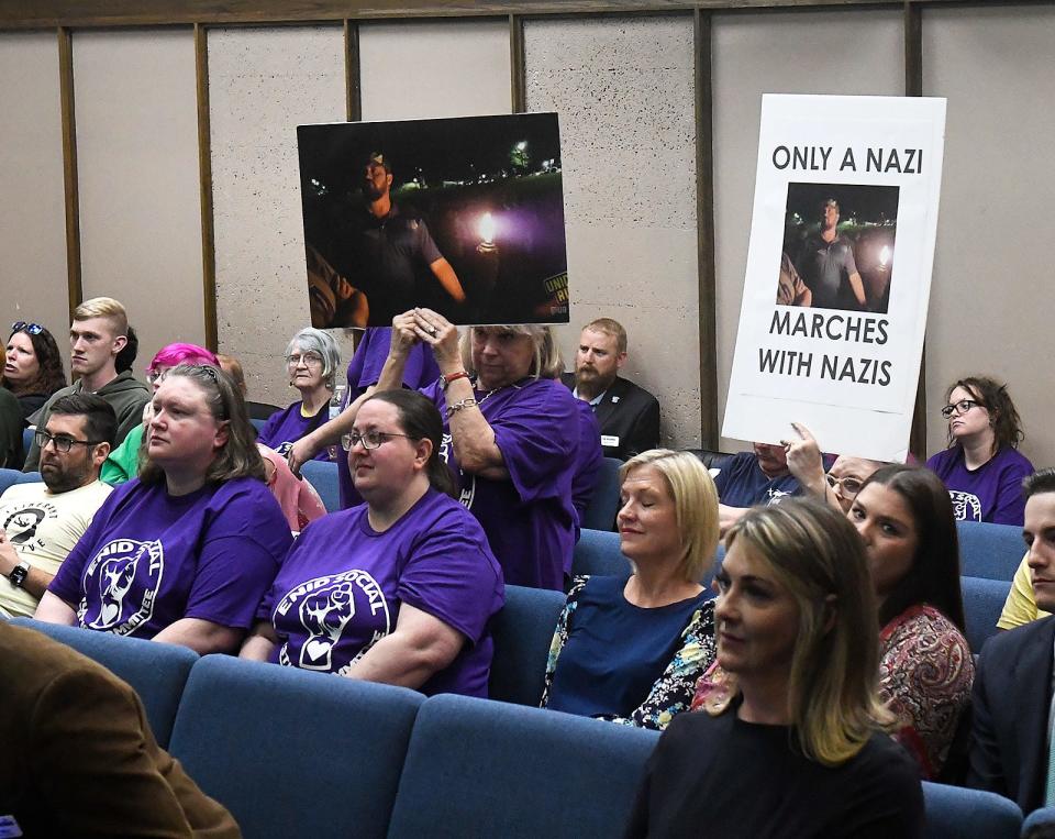 Members of the Enid Social Justice Committee hold protest signs May 1 as new Enid city commissioner, Judd Blevins, takes the oath of office during the city council meeting.