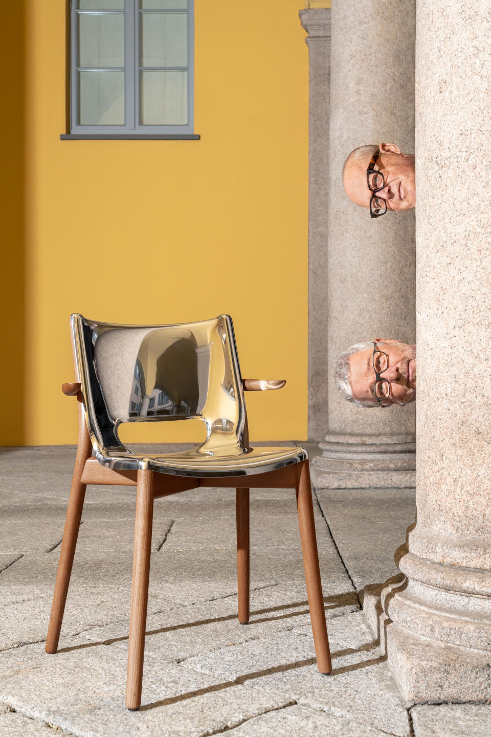 Alberto Alessi (top) and Philippe Starck (bottom) posing beside Alessi's Poêle chair.