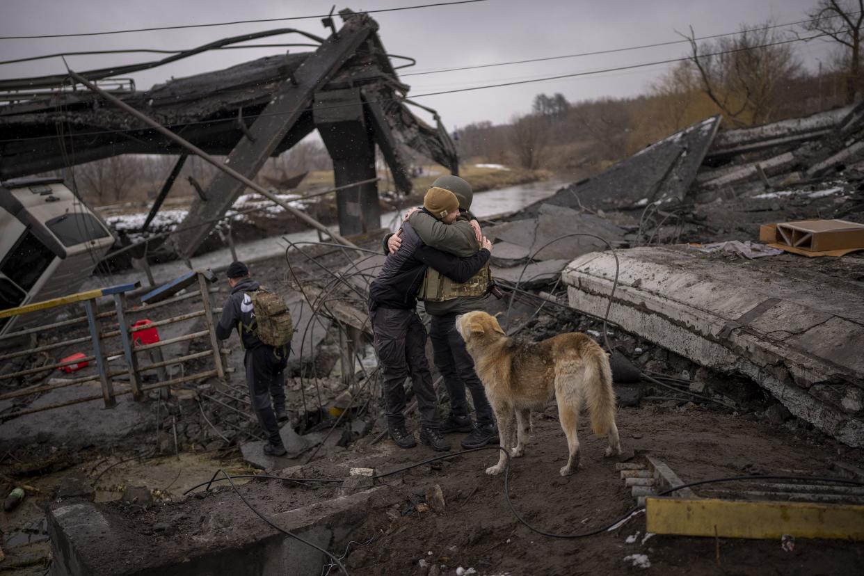 Two militiamen hug as they meet crossing a destroyed bridge on the outskirts of Kyiv, Ukraine, Wednesday, March 2. 2022. Russia renewed its assault on Ukraine’s second-largest city in a pounding that lit up the skyline with balls of fire over populated areas. That came Wednesday even as both sides said they were ready to resume talks aimed at stopping the new devastating war in Europe.