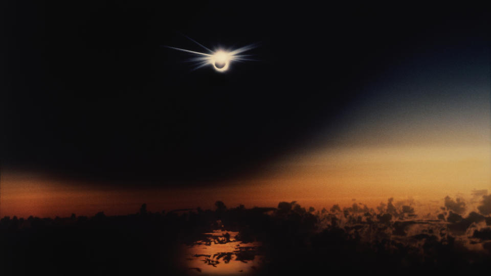 A solar eclipse over the Pacific Ocean at sunset, with the 