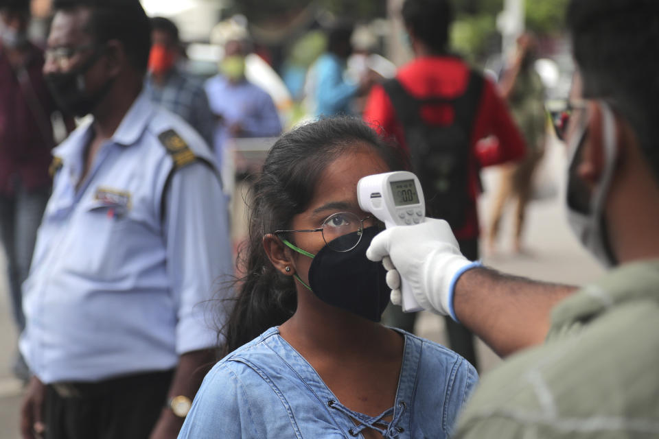 An official checks the body temperature of a candidate wearing a face mask as a precaution against coronavirus before appearing for National Eligibility cum Entrance Test ( NEET) at an exam centre in Hyderabad, India, Sunday, Sept. 13, 2020. NEET is for students who wish to study undergraduate medical and dental courses in government or private medical colleges in India. India's coronavirus cases are now the second-highest in the world and only behind the United States. (AP Photo/Mahesh Kumar A.)