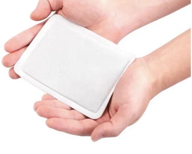 Two hands holding a white Adhesive Body Warmer Patch against a white background.