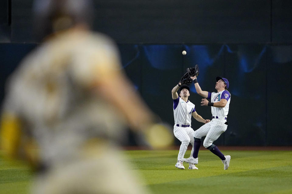 Arizona Diamondbacks' Jake McCarthy, right, catches a fly-out by San Diego Padres' Ha-Seong Kim as he avoids colliding with teammate Corbin Carroll during the third inning of a baseball game, Saturday, Aug. 12, 2023, in Phoenix. (AP Photo/Matt York)
