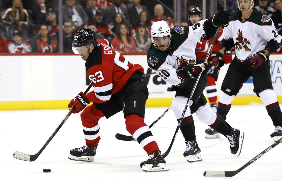 New Jersey Devils left wing Jesper Bratt (63) skates with the puck against Arizona Coyotes defenseman Sean Durzi (50) during the second period of an NHL hockey game Friday, Oct. 13, 2023, in Newark, N.J. (AP Photo/Noah K. Murray)