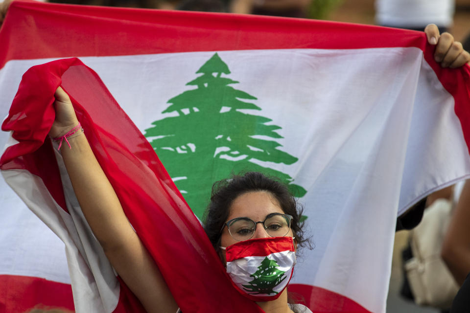 An anti-government protester shouts slogans while wearing a mask with the colors of the Lebanese flag in Beirut, Lebanon, Thursday, July 2, 2020. Major retailers in Lebanon announced Thursday they will temporarily close in the face of an increasingly volatile currency market and their inability to set prices while the local currency tumbles before the dollar. (AP Photo/Hassan Ammar)