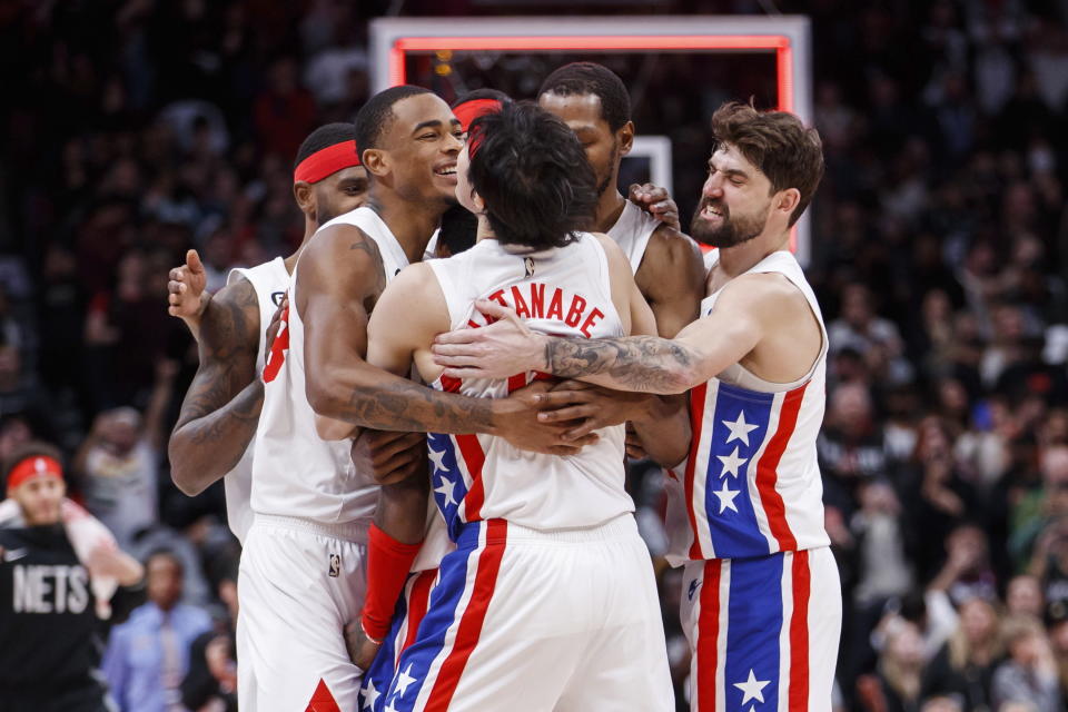 Brooklyn Nets guard Kyrie Irving (obcscured) is embraced by teammates after hitting the winning shot against the Toronto Raptors during an NBA basketball game in Toronto, Friday, Dec. 16, 2022. (Cole Burston/The Canadian Press via AP)