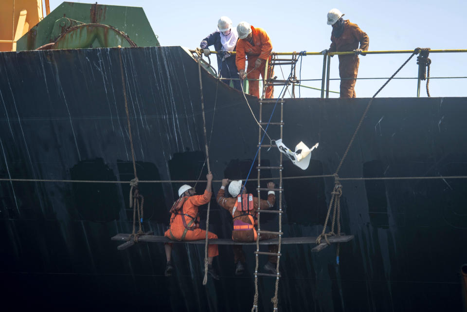 Crew members of the Grace 1 super tanker remove the name of ship in the British territory of Gibraltar, Saturday, Aug. 17, 2019. The shipping agent for an Iranian supertanker caught in a diplomatic standoff says the vessel is ready to depart Gibraltar in "24 to 48 hours," despite a last-minute effort by the United States to seize it again. (AP Photo/Marcos Moreno)