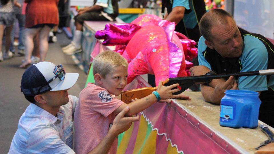 A father and son enjoy a shooting game at the Venetian Festival carnival on Saturday, July 22.