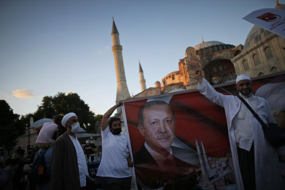 People holding a banner with the image of Turkey's President Recep Tayyip Erdogan', celebrate, outside the Byzantine-era Hagia Sophia, one of Istanbul's main tourist attractions in the historic Sultanahmet district of Istanbul, following Turkey's Council of State's decision, Friday, July 10, 2020.Turkey's highest administrative court issued a ruling Friday that paves the way for the government to convert Hagia Sophia - a former cathedral-turned-mosque that now serves as a museum - back into a Muslim house of worship. The Council of State threw its weight behind a petition brought by a religious group and annulled a 1934 cabinet decision that changed the 6th century building into a museum.(AP Photo/Emrah Gurel)