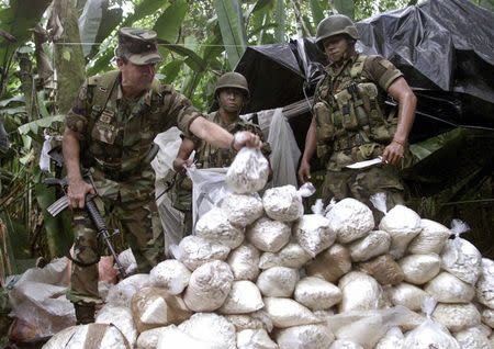 Colombian Army Gen. Mario Montoya (L) examines a cocaine pack confiscated by troops near Puerto Asis, Putumayo province, in this February 12, 2001 file photo. Hundreds of thousands of Colombians in frontline areas want President Juan Manuel Santos re-elected on Sunday so he can continue negotiating an end to five decades of war with guerrilla leaders of the Revolutionary Armed Forces of Colombia (FARC). REUTERS/Eliana Aponte/Files