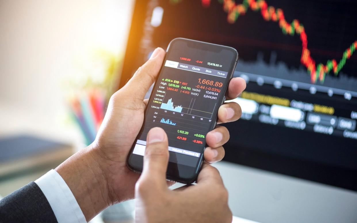 Investor analyzing stock market investments with financial dashboard on smartphone and computer screens