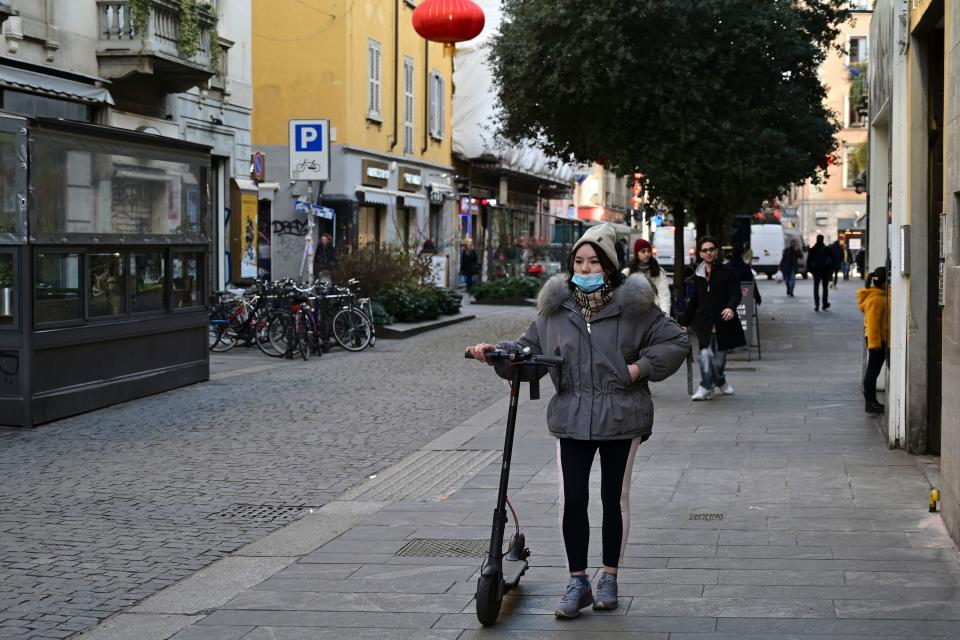 A woman wearing a mask walks by her electric scooter in via Paolo Sarpi, the commercial street of the chinese district of Milan on January 30, 2020. - Several well-known figures in the Chinese community in Italy on January 30, 2020 denounced &quot;Discrimination without distinction&quot; and &quot;latent racism&quot; from Italians frightened by the coronavirus epidemic and the risks of contagion. (Photo by Miguel MEDINA / AFP) (Photo by MIGUEL MEDINA/AFP via Getty Images)
