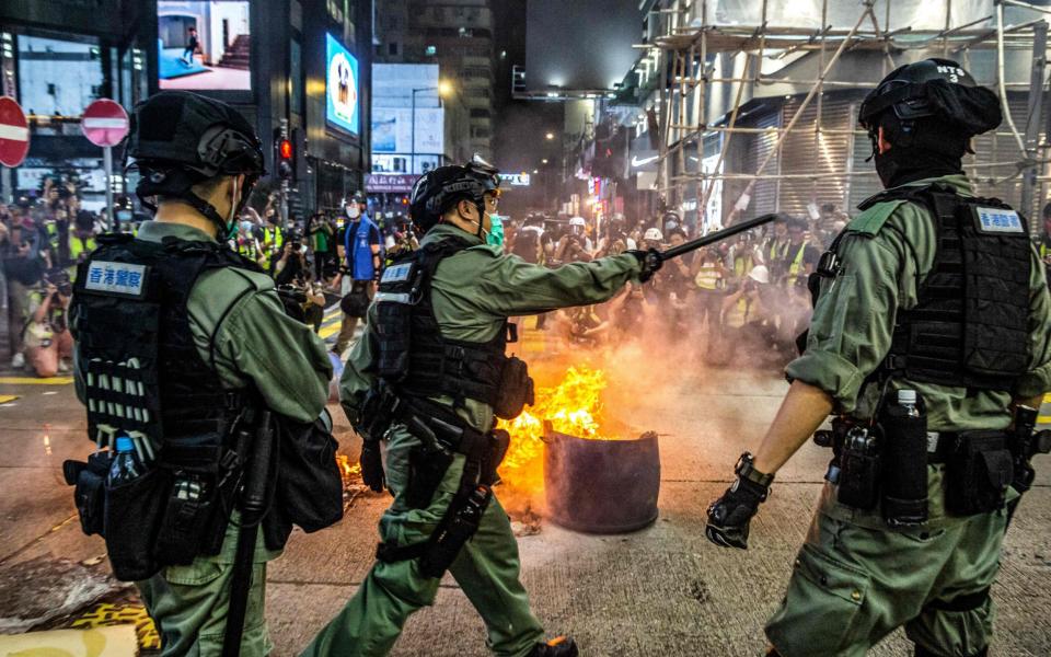 Police stand guard on a road to deter pro-democracy protesters from blocking roads  - AFP