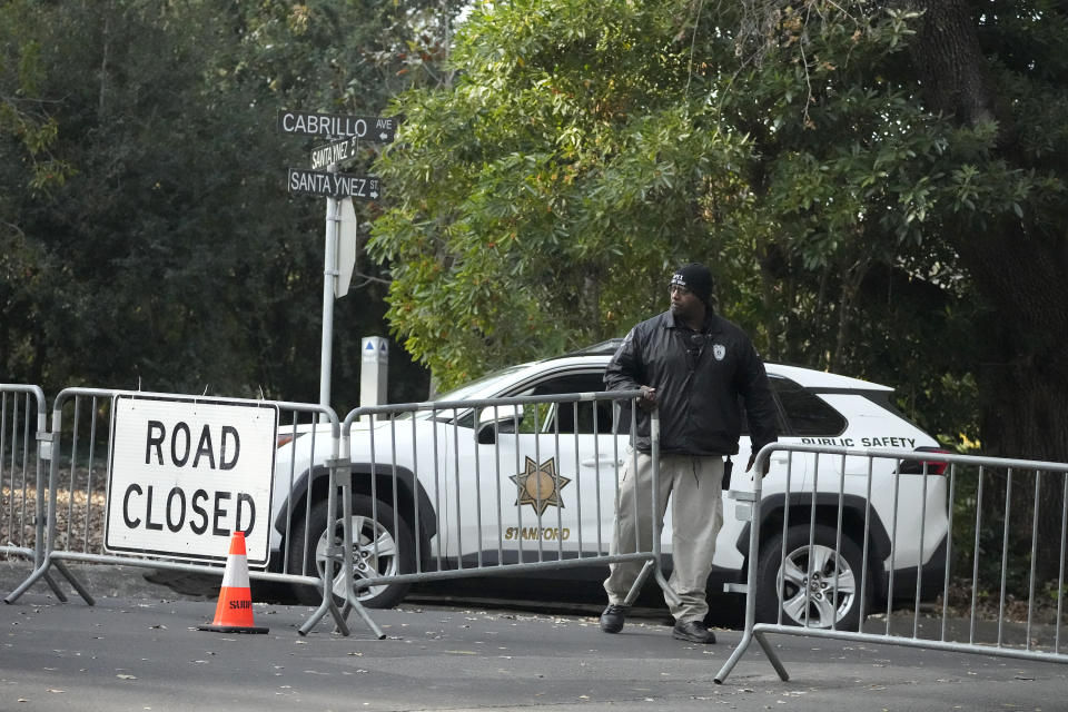 A guard closes barricades to a street near the family home of FTX founder Sam Bankman-Fried in Palo Alto, Calif., Friday, Dec. 23, 2022. Bankman-Fried's parents agreed to sign a $250 million bond and keep him at their California home while he awaits trial on charges that he swindled investors and looted customer deposits on his FTX trading platform. (AP Photo/Jeff Chiu)