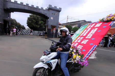 A courier carrying a flower board from supporters of former Jakarta governor Basuki Tjahaja Purnama arrives at the Mobile Police Brigade or Brimob headquarters where he is being detained, in Depok, south of Jakarta, Indonesia May 10, 2017 in this photo taken by Antara Foto. Antara Foto/Yulius Satria Wijaya/ via REUTERS