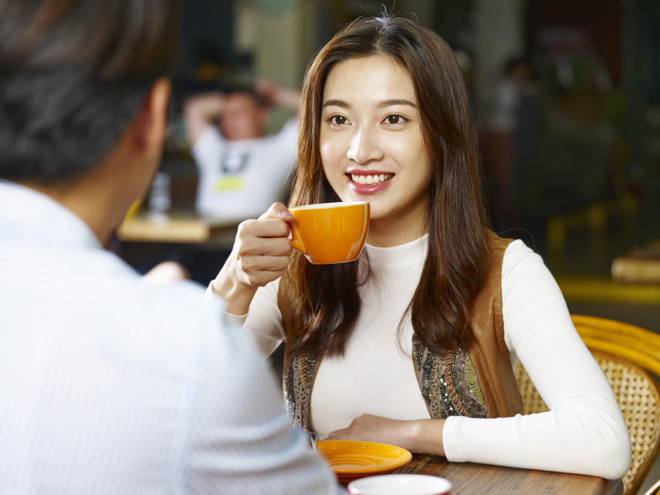 A young woman drinks coffee at a cafe.