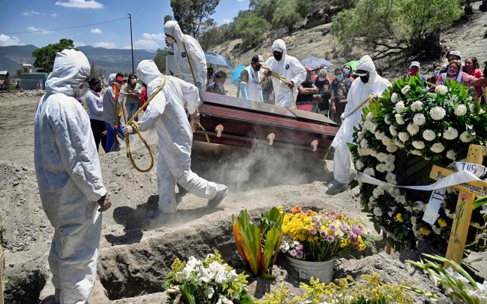 Workers bury an alleged victim of Covid-19 at the Municipal Pantheon of Valle de Chalco, in Mexico - ALFREDO ESTRELLA/AFP