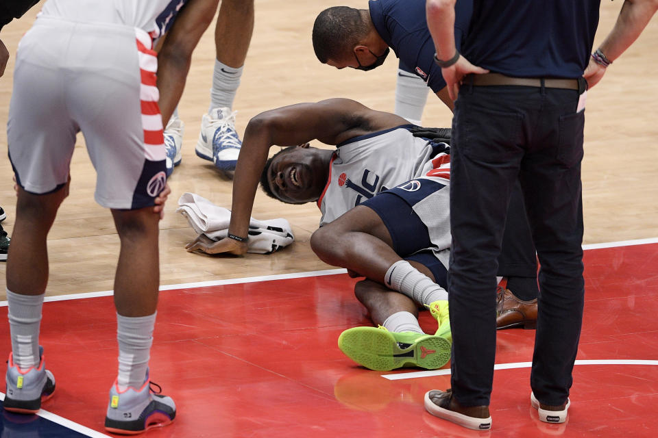 Washington Wizards center Thomas Bryant, center, lies injured on the court during the first half of an NBA basketball game against the Miami Heat, Saturday, Jan. 9, 2021, in Washington. (AP Photo/Nick Wass)