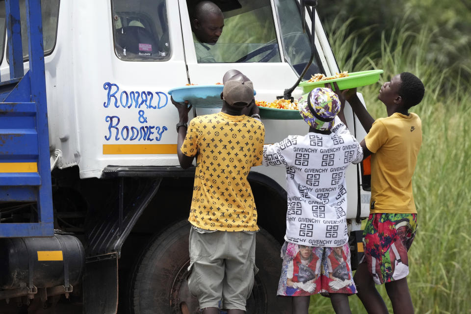 Un grupo de jóvenes venden hongos silvestres a unos automovilistas en las afueras de Harare, Zimbabue, el martes 21 de febrero de 2023. (AP Foto/Tsvangirayi Mukwazhi)