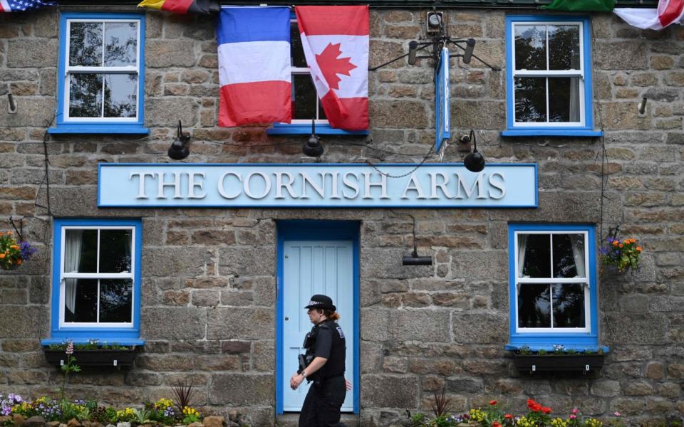 A British police officer walks past The Cornish Arms gastropub in St Ives - AFP