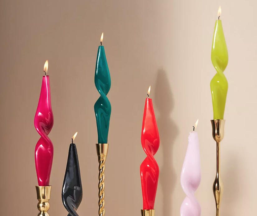  colorful twisted glossy candles stacked at different heights on gold candlesticks 