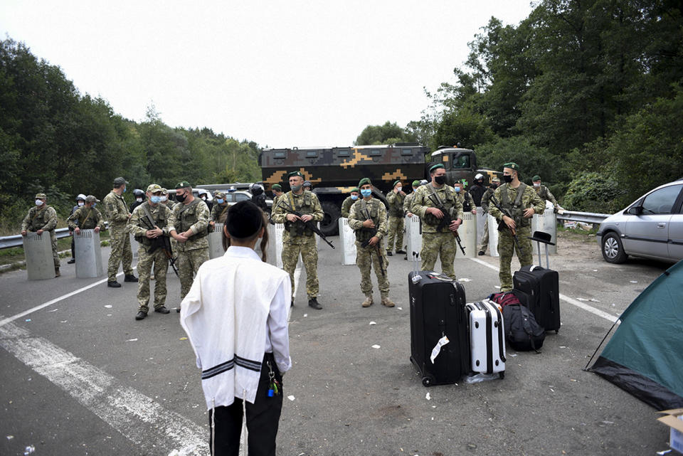 Ukrainian border guards block the road on the Belarus-Ukraine border, in Belarus, Tuesday, Sept. 15, 2020. About 700 Jewish pilgrims are stuck on Belarus' border due to coroavirus restrictions that bar them from entering Ukraine. Thousands of pilgrims visit the city each September for Rosh Hashana, the Jewish new year. However, Ukraine closed its borders in late August amid a surge in COVID-19 infections. (TUT.by via AP)