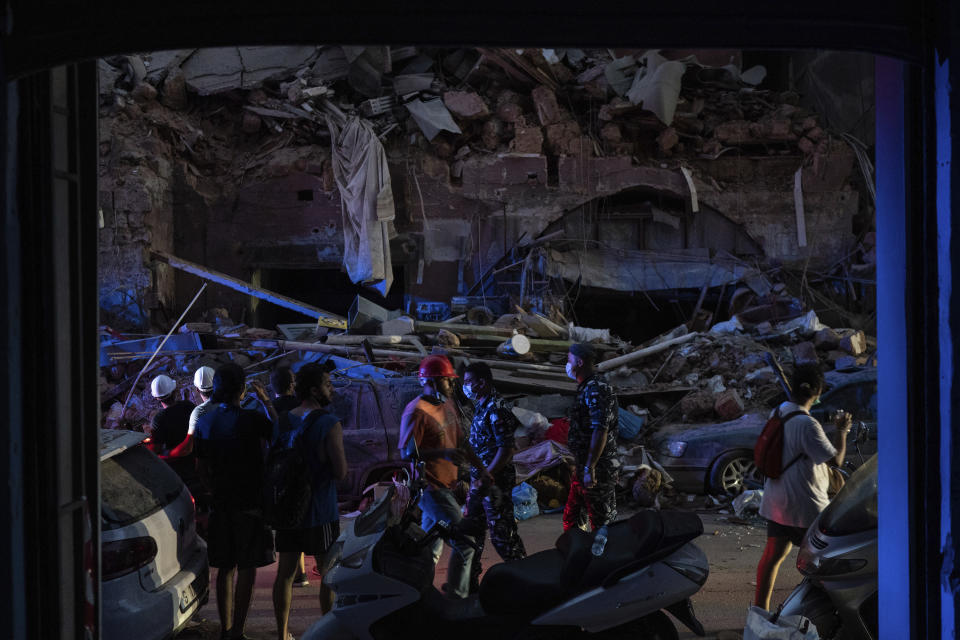 People walk by damaged buildings at a neighborhood near the scene of Tuesday's explosion that hit the seaport of Beirut, Lebanon, Friday, Aug. 7, 2020. Rescue teams were still searching the rubble of Beirut's port for bodies on Friday, nearly three days after a massive explosion sent a wave of destruction through Lebanon's capital, killing over a hundred people and wounding thousands. (AP Photo/Felipe Dana)