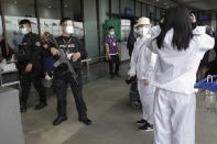 A policeman reminds passengers to wear their face shields properly at Manila's International Airport, Philippines, Monday, Jan. 18, 2021. Coronavirus infections in the Philippines have surged past 500,000 in a new bleak milestone with the government facing criticisms for failing to immediately launch a vaccination program amid a global scramble for COVID-19 vaccines. (AP Photo/Aaron Favila)