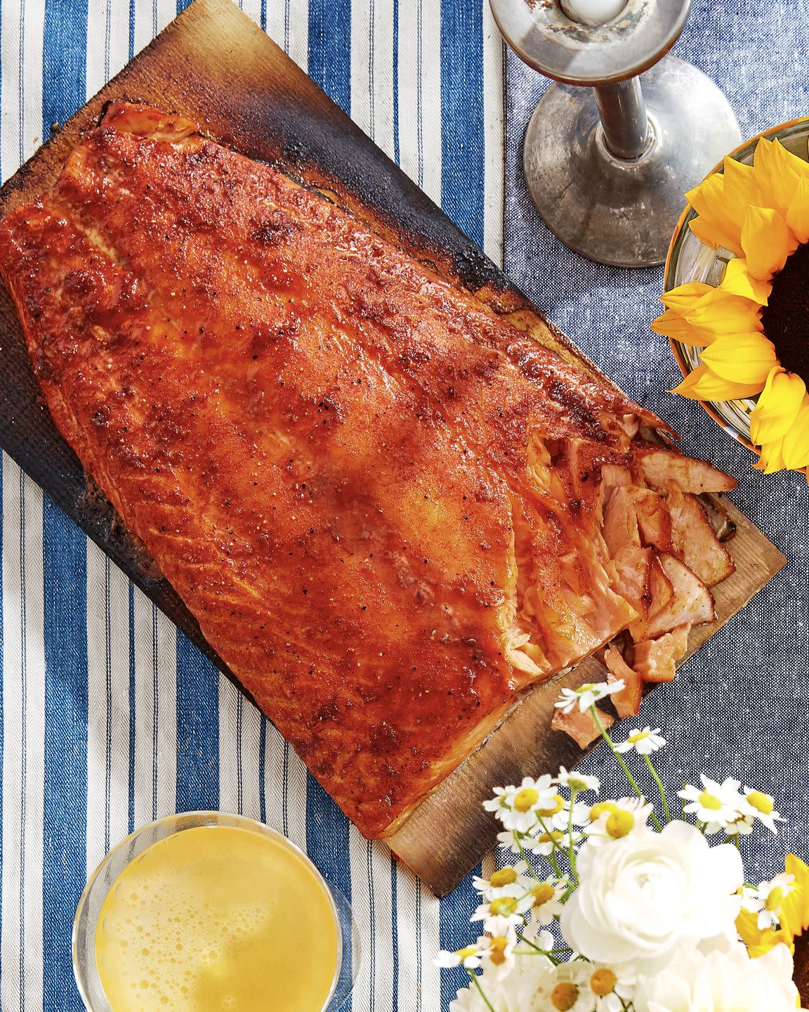 sweet and smoky cedar planked salmon on a cedar plank on a blue and white striped linen table cloth