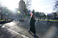 A man carries a U.S. flag past National Guard members standing behind a perimeter fence, Sunday, Jan. 10, 2021, at the Capitol in Olympia, Wash. With the FBI warning of potential violence at all state capitols Sunday, Jan. 17, the ornate halls of government and symbols of democracy looked more like heavily guarded U.S. embassies in war-torn countries. (AP Photo/Ted S. Warren)