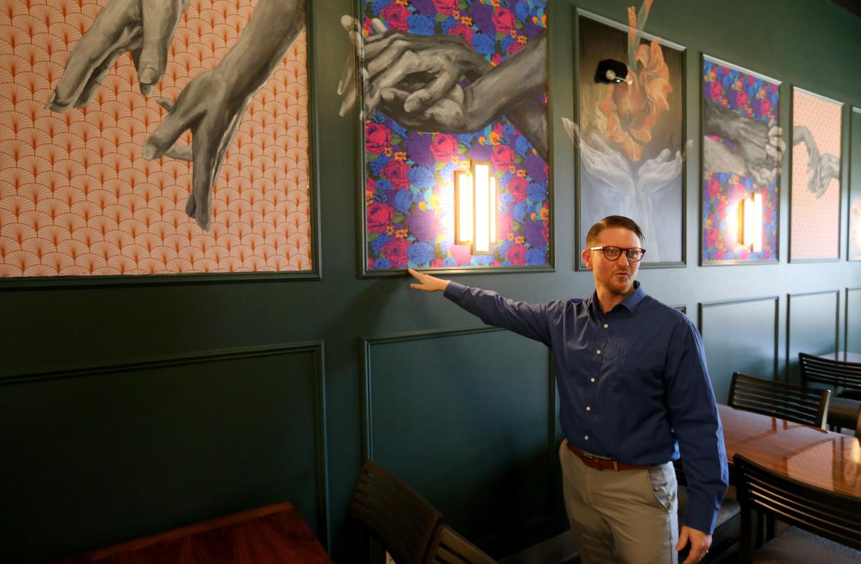 Casey Dvorak, general manager and sommelier of the LaSalle Hospitality Group, shows the work of local artist Lauren Steinhofer that is on the walls Monday, March 11, 2024, at the L Wine Bar at 530 E. Lexington Ave. in Elkhart. The site formerly was the 530 Wine Bar.