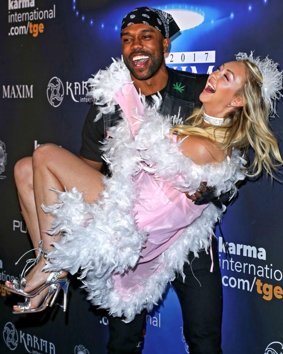 A man playfully lifts up a woman at a Halloween party.