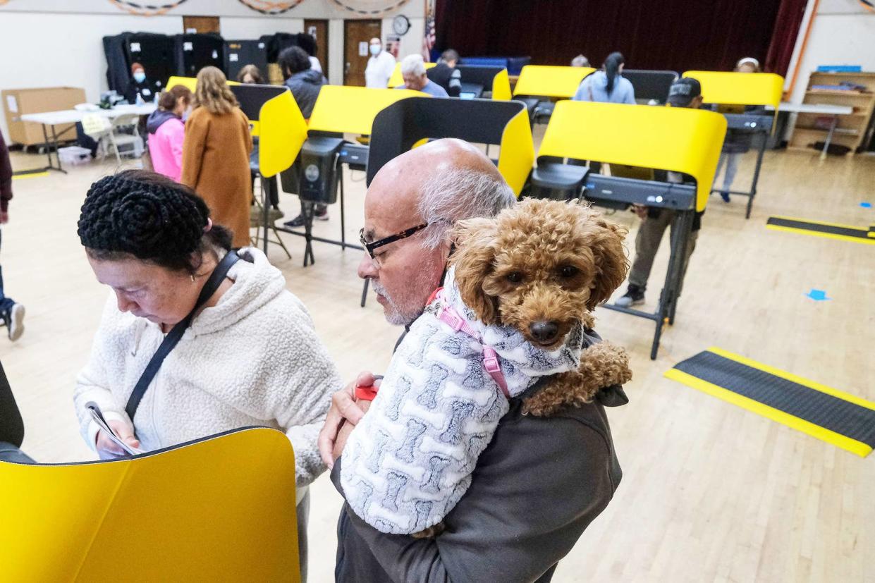 Feel Flores, 67, holds his dog Lulu as they wait while his wife, Ana Marina, 67, casts her ballot at a vote station on Nov. 8, 2022, in Los Angeles.