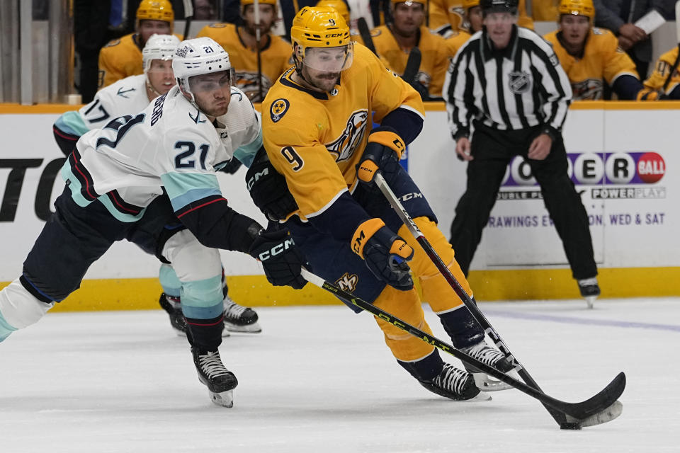 Nashville Predators left wing Filip Forsberg (9) tries to get the puck past Seattle Kraken center Alex Wennberg (21) during the second period of an NHL hockey game Thursday, Oct. 12, 2023, in Nashville, Tenn. (AP Photo/George Walker IV)